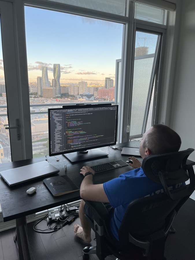 Andrei Trubin working at his home desk overlooking the city skyline